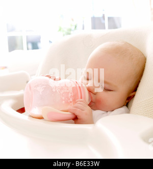 Sleeping baby girl (6-11 mois)tenant une bouteille de lait dans sa bouche Banque D'Images