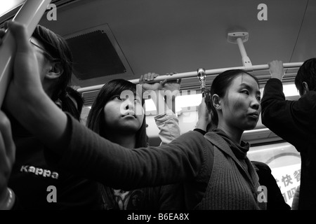Deux femmes chinoises se pateintly sur métro bondé en pleine réflexion. Chines population croissante est à la naissance : 1,11 homme(s)/femme Banque D'Images