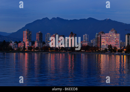 Rouge dernier rayons de soleil reflété dans West End Vancouver immeubles de grande hauteur au crépuscule avec la montagne Grouse de Vanier Park Banque D'Images