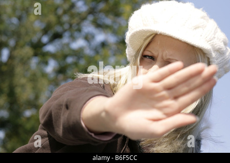 Jeune femme blonde à l'aide fait un geste de défense avec sa main Banque D'Images