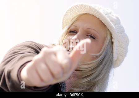 Jeune femme blonde avec capuchon fait thumb up Banque D'Images