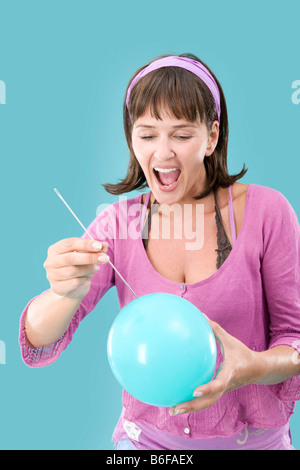 Fille coller une aiguille dans un ballon Banque D'Images