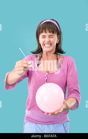 Fille coller une aiguille dans un ballon Banque D'Images