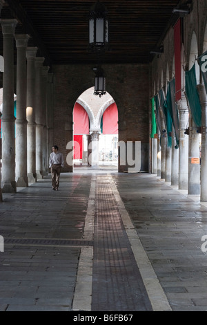 Homme marchant à travers un passage couvert à arcades à Venise, Italie, Europe Banque D'Images