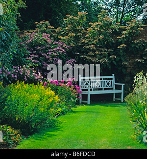 Siège romantique dans un jardin clos avec fleurs colorées Banque D'Images