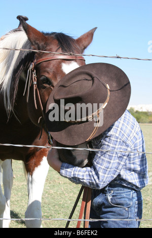 Un jeune cow-boy kissing son cheval sur le ranch à l'intérieur de l'Alpage Banque D'Images