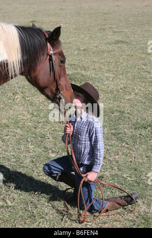 Un jeune cow-boy kissing son cheval sur le ranch Banque D'Images