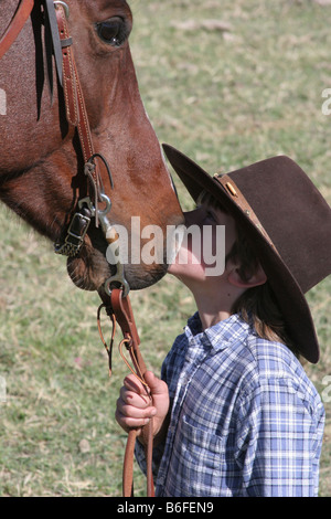 Un jeune cow-boy kissing son cheval sur le ranch Banque D'Images