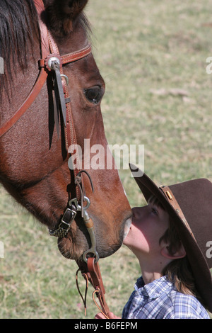 Un jeune cow-boy kissing son cheval sur le ranch Banque D'Images