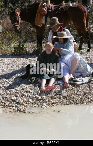 Une famille et le cheval sur le bord du cours d'eau bénéficiant de temps ensemble maman tressage des cheveux des filles Banque D'Images