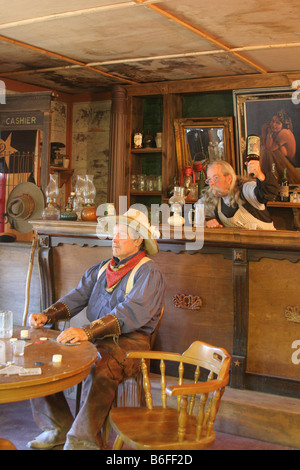 Dans un vieux saloon un cowboy de l'ouest est sur le point d'être frappé à la tête par le barman pour ne pas payer Banque D'Images