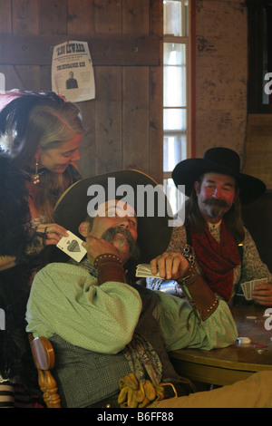 Un saloon girl aider un cowboy de plagiat en un jeu de poker avec une carte Ace Banque D'Images