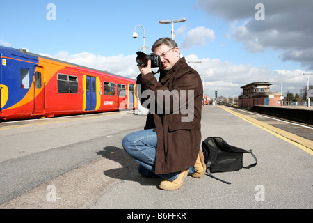 Steve, un passionné de chemins de fer, est de prendre des photos de trains en gare de Wimbledon, Londres Banque D'Images