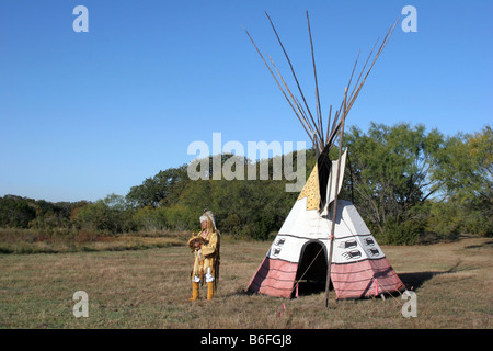 Apache un Native American Indian de battre son tambour devant son tipi Banque D'Images