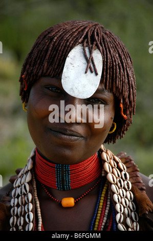 Souriante jeune femme noire portant un collier de coquillages kauri, une plaque métallique sur son front et d'argile dans ses cheveux, près de l'Tur Banque D'Images