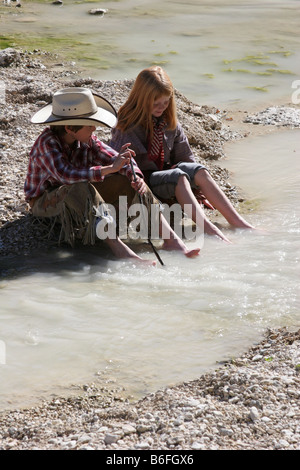 Une jeune fille de cow-boy et la période d'échange avec leurs pieds dans un ruisseau Banque D'Images