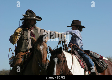 Un cowboy père montrant son fils comment corde une vache sur le ranch Banque D'Images