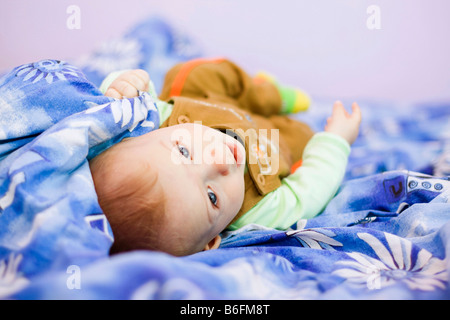 Bébé garçon, 7 mois, sur le lit Banque D'Images