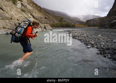 Jeune femme, backpacker, randonneur marchant dans les ruisseaux, montagnes St., Donjek Route, la réserve de parc national Kluane, Yukon Te Banque D'Images