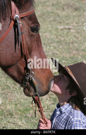 Un jeune cow-boy kissing son cheval sur le ranch Banque D'Images