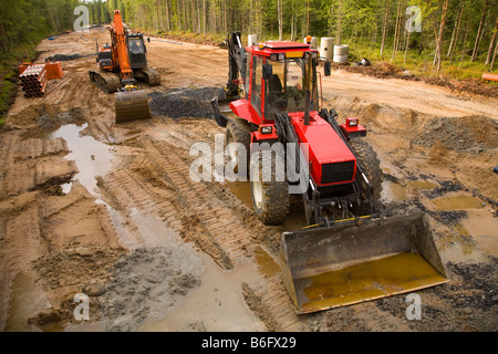 Tracteur et digger au site travaux routiers , construction d'une nouvelle route de forêt , Finlande Banque D'Images