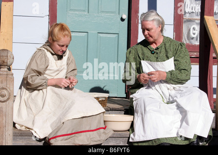 La figure d'une grand-mère et de la jeune fille l'accrochage haricots sur leur longère porche dans le pays Banque D'Images