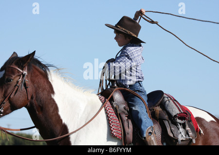 Un jeune cowboy jetant une corde de cheval dans un ranch au Texas Banque D'Images