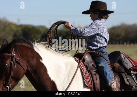 Un jeune cowboy obtenir prêt à jeter la corde de cheval Banque D'Images