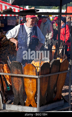 Homme principal préparant des filets de saumon cuits lentement à l'aide d'un feu ouvert à l'extérieur de la foire de marché aux poissons de Kalaryssäys Kalaryssaiys à Kuopio City Finland Banque D'Images