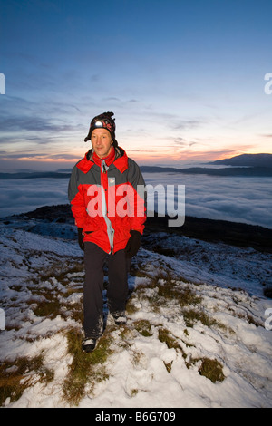 Un marcheur sur Wansfell Pike dans le Lake District UK avec le brouillard de la vallée ci-dessous Banque D'Images