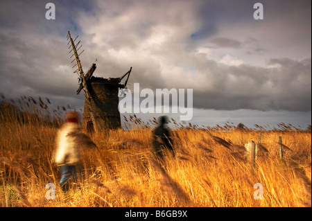 Les chiffres des deux flous fantomatiques promeneurs sont capturés ici contre l'usine à l'abandon d'Brograve sur les Norfolk Broads Banque D'Images