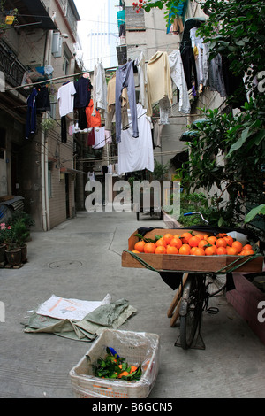 Ruelle latérale avec la communauté de pendaison blanchisserie sèche sur des tiges de bambou et de fruits frais dans les rues afin d'être vendus Guangzhou Banque D'Images