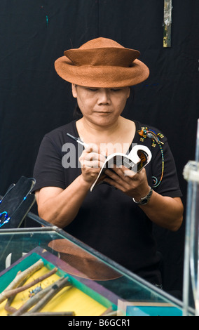 Artiste lit livre, prend des notes, à la foire artisanale stand de vente. Banque D'Images