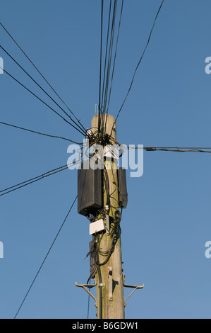 Lignes de téléphone rayonnant à partir du haut d'un poteau télégraphique against a blue sky UK Banque D'Images