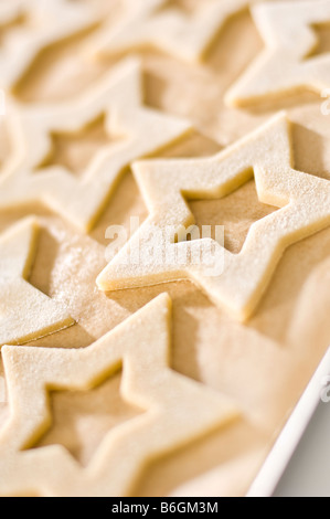 Biscuits au gingembre en forme d'étoiles portées sur le papier avant la cuisson. Ensuite emballées dans de petites boîtes pour les cadeaux de Noël. Banque D'Images