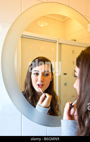 Close up portrait of vertical d'une attractive young woman putting on lustre de lèvre dans un miroir de salle de bains Banque D'Images