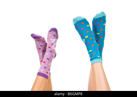 Close up portrait of horizontal de deux paires de pieds croisés portant des chaussettes éparses dans l'air sur un fond blanc. Banque D'Images