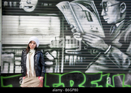 Jeune femme à la mode se tenait contre un mur de graffiti Banque D'Images