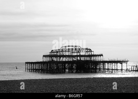 Une image en noir et blanc de la Burnt Out West Pier de Brighton reste sur une journée calme, prises de la plage de Brighton Banque D'Images