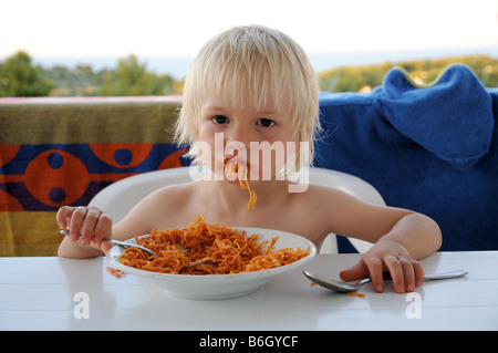 Un jeune garçon de manger des pâtes en vacances en Italie. Banque D'Images