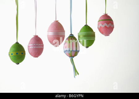 Six oeufs de Pâques colorés colorés suspendus dans une rangée Banque D'Images
