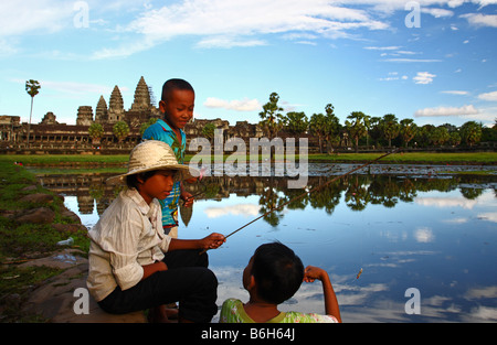 Trois enfants de la pêche dans le petit étang devant Angkor Wat temple principal, au Cambodge Banque D'Images