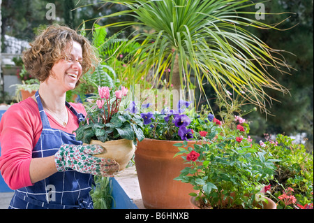 Femme tenant un pot de cyclamen dans son jardin Banque D'Images