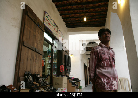 Homme debout en face d'un magasin de chaussures au marché Souq Waqif à Doha, Qatar. Banque D'Images