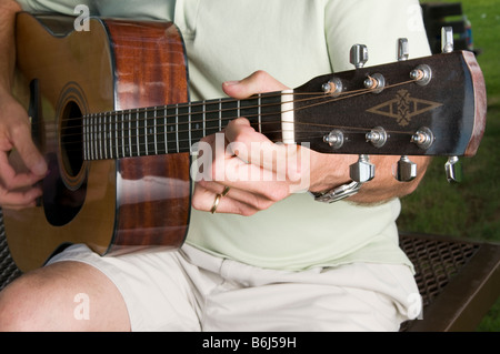 Close up of middle aged man playing guitar dans le parc Banque D'Images