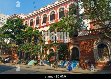 Gens campés à l'extérieur d'un grand bâtiment dans le Nord de Kolkata, Inde Banque D'Images