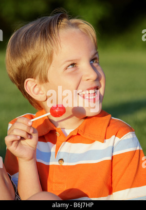 Happy young white boy eating a sucker Banque D'Images