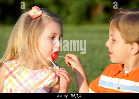 Petit garçon et fille partageant une sucette bonbon Banque D'Images