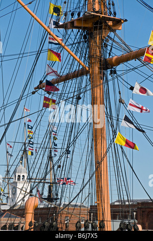 Regardant à travers le gréement du HMS Warrior pour les mâts HMS Victory en arrière-plan le port de Portsmouth, Hampshire, Angleterre Banque D'Images