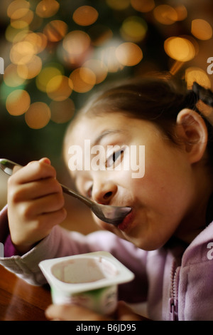Petite fille de cinq ans mange yaourt de pot Banque D'Images